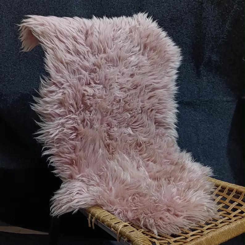 Warm pink sheepskin rug draped over a woven lounge chair