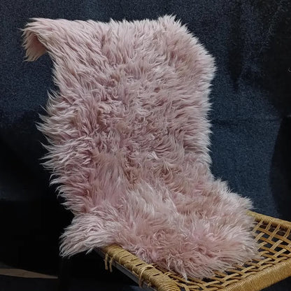 Warm pink sheepskin rug draped over a woven lounge chair